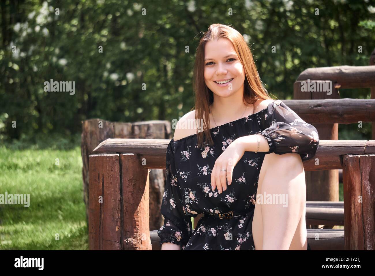 smiling pretty girl sitting on a park bench in a relaxed pose Stock ...