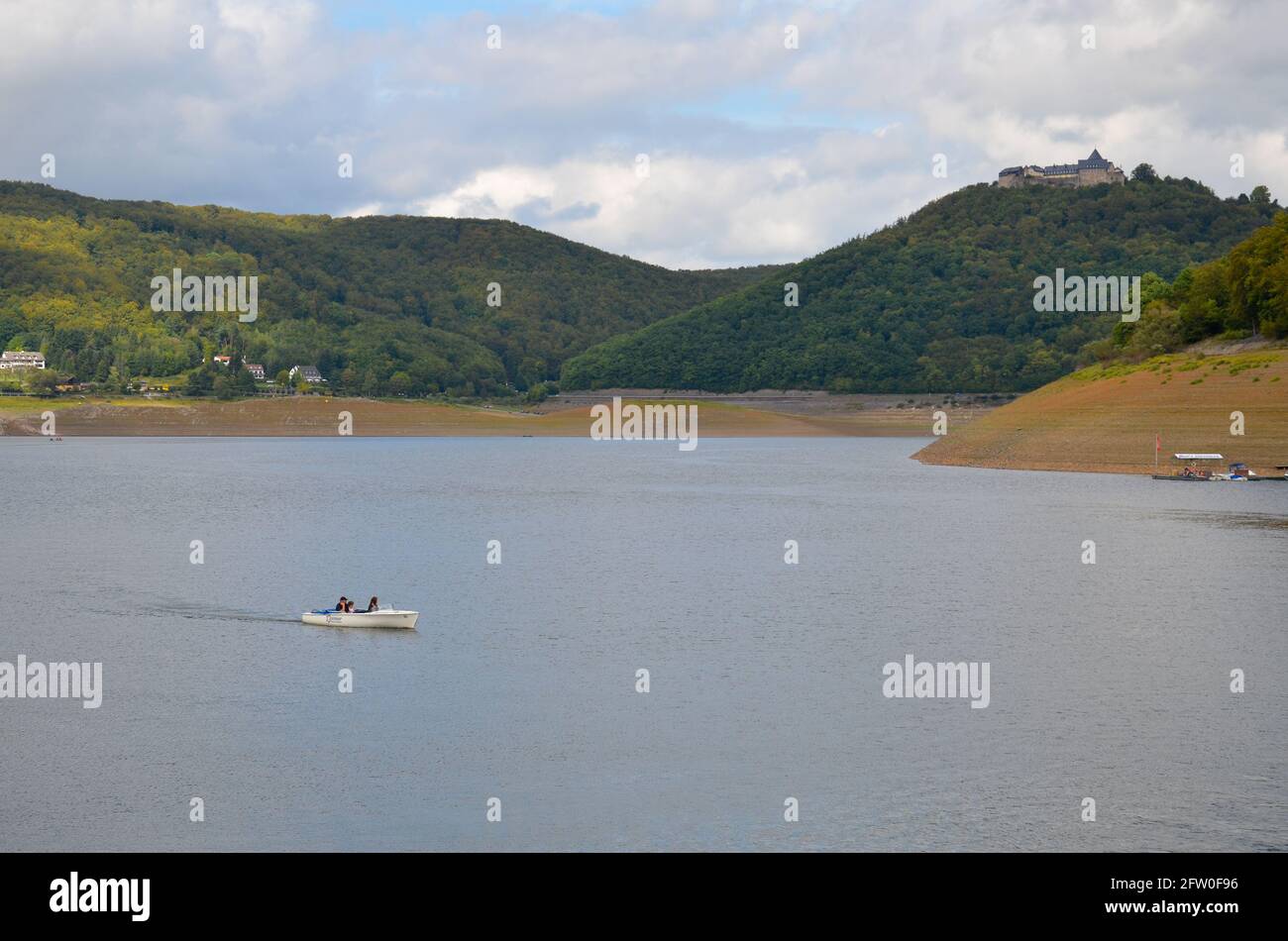 Edersee, Hessen, Germany - September 10 2011: View of the Edersee with the Waldeck fortress and mountains in the background and a small boat Stock Photo