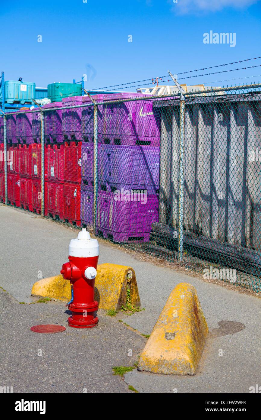 Fire hydrant on an industrial road with concrete barries and coloured fish containers in Steveston British Columbia Canada Stock Photo