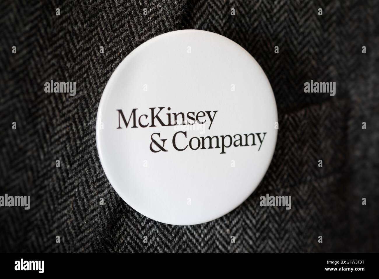 A button badge bearing the logo of McKinsey & Company fastened to a suit jacket. Stock Photo