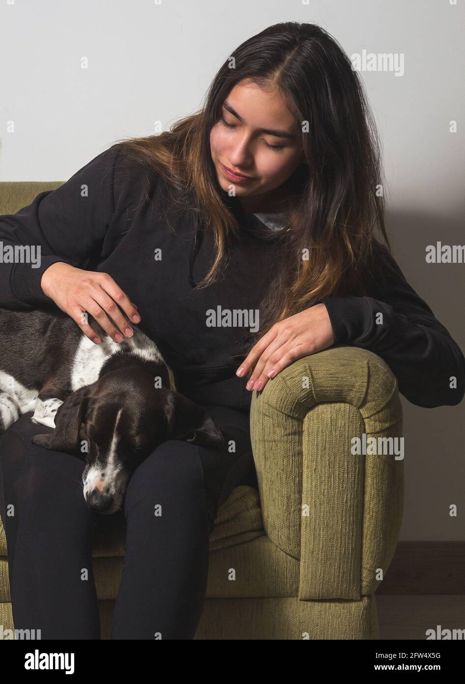 Portrait of a teenage girl smiling and petting her black and white ...