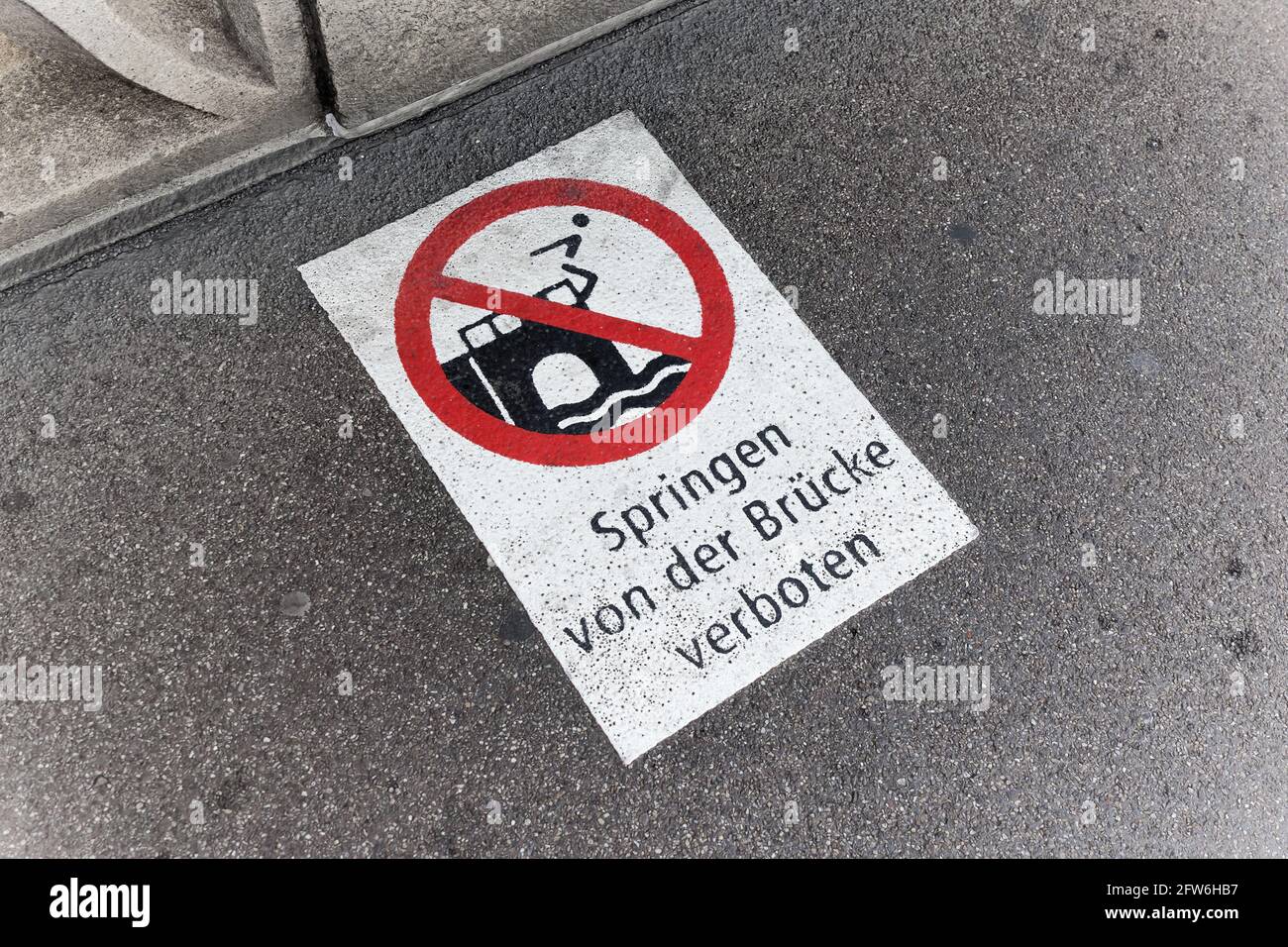 red white prohibition sign painted on the asphalt, german text sign, german text translation: jumping from the bridge prohibited Stock Photo