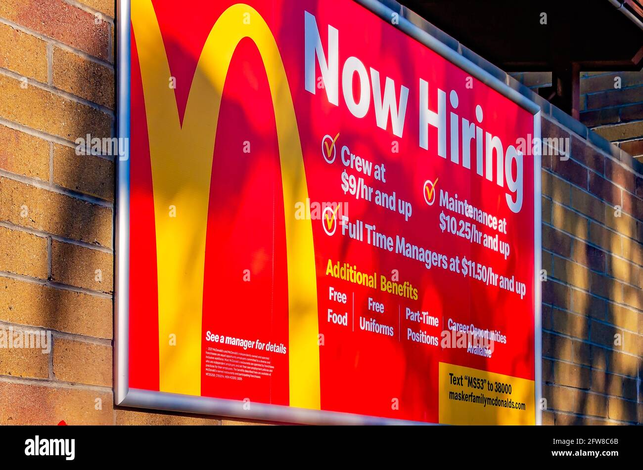 A “now hiring” sign lists benefits of the job at McDonald’s on Highway 90, May 8, 2021, in Biloxi, Mississippi. Stock Photo