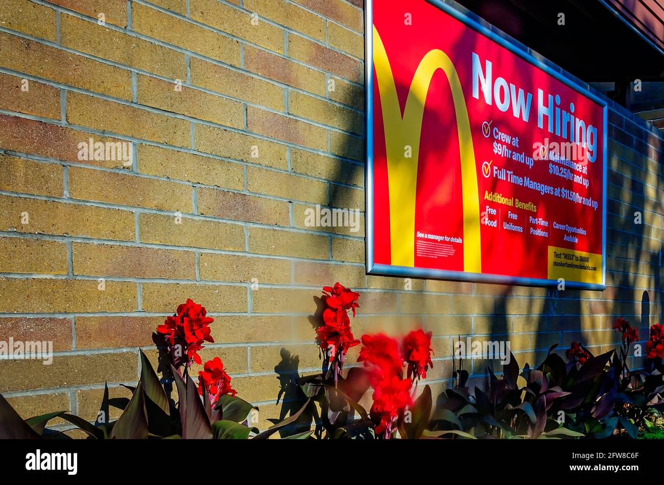 A “now hiring” sign lists benefits of the job at McDonald’s on Highway 90, May 8, 2021, in Biloxi, Mississippi. Stock Photo
