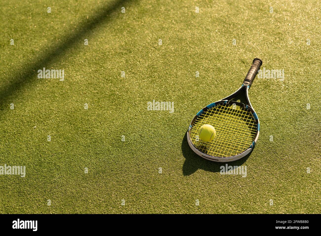 A tennis racket and new tennis ball on a freshly painted tennis court