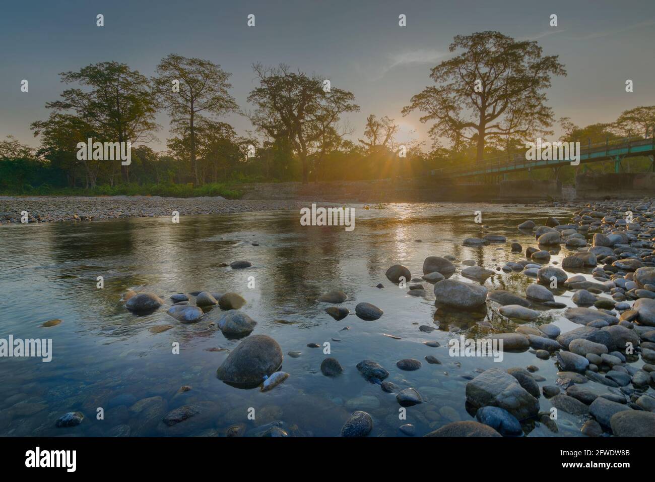 Beautiful sunrise over Murti river, riverbed in foreground with flowing water and stones. Scenic beauty of Dooars landscape, West Bengal, India Stock Photo