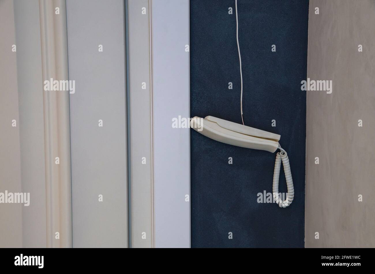 Vintage telephone receiver hanging on a wire on a light background with copy space. Stock Photo
