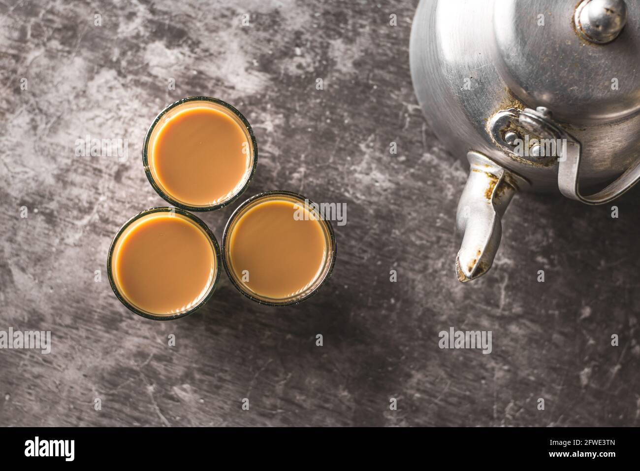 Indian chai in glass cups with metal kettle and other masalas to make