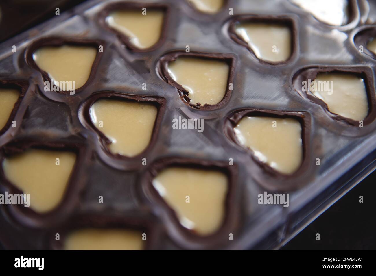 Closeup of chocolate molds in the shape of hearts full of sweet creamy