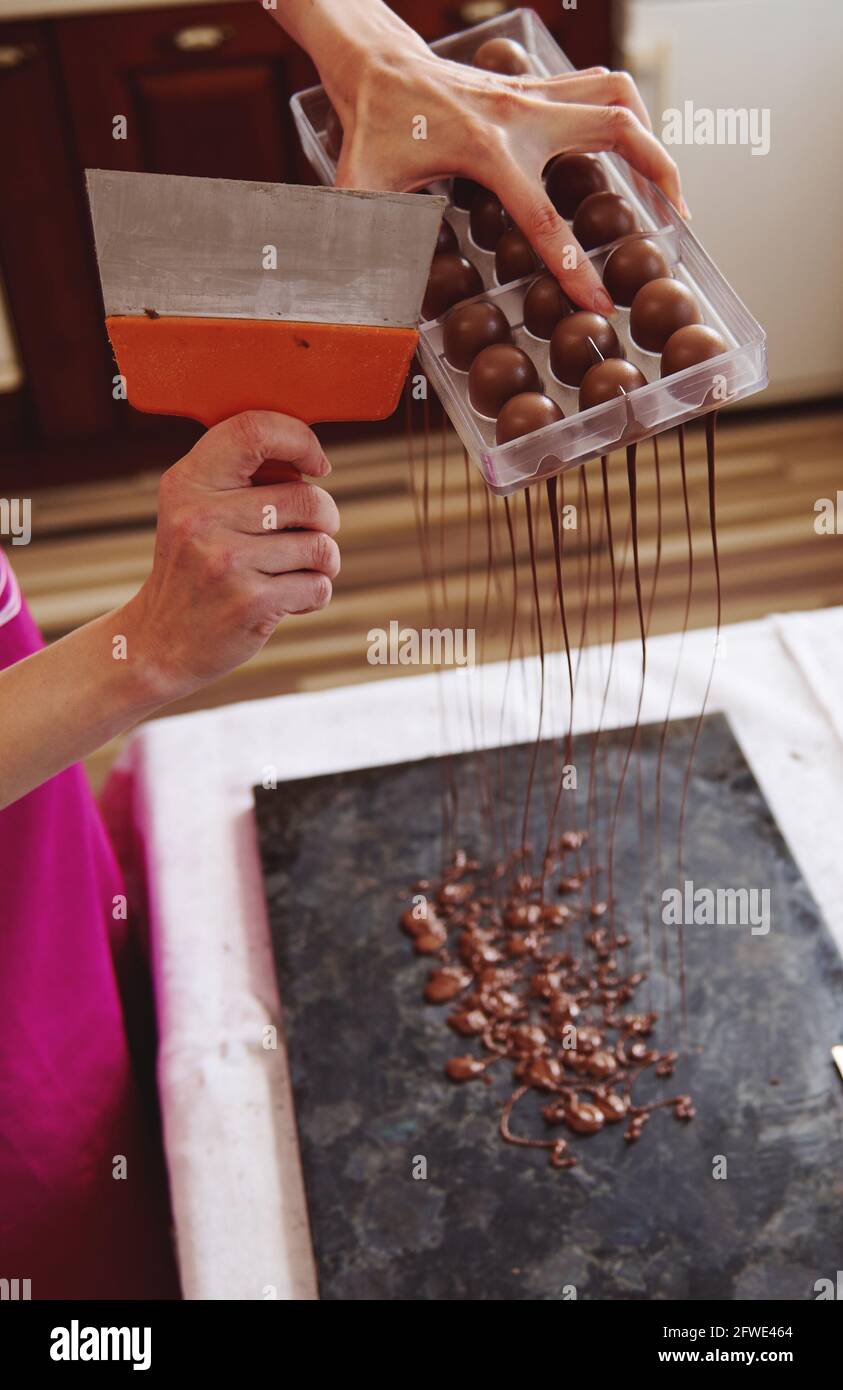 Closeup of using cake scraper to remove excess chocolate from molds