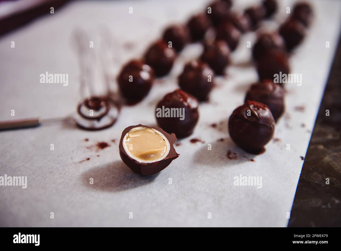 Chocolate truffles on parchment paper and accent in the foreground with