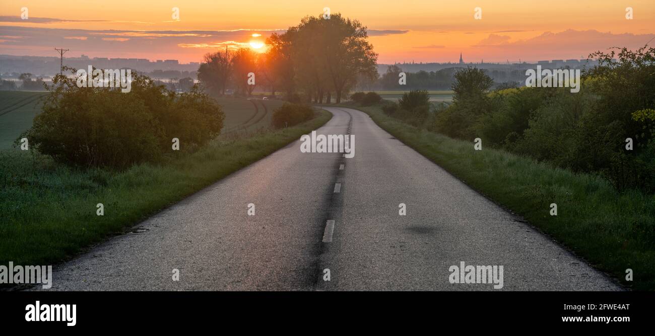Asphalt road running through the countryside at sunrise Stock Photo