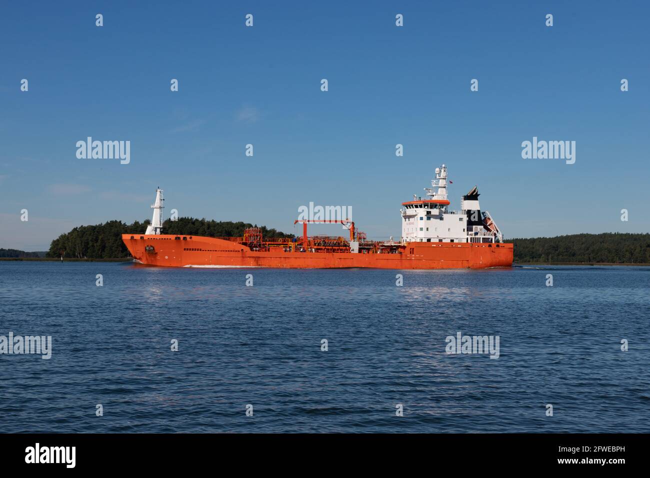 Orange oil/chemical tanker leaving Naantali oil refinery and passing Ruissalo island. Stock Photo