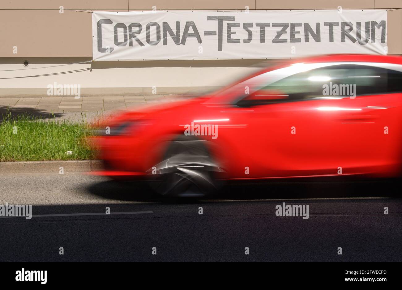 Dresden, Germany. 22nd May, 2021. A red car drives past a banner reading 'Corona Test Centre' in the Johannstadt district. Credit: Robert Michael/dpa-Zentralbild/dpa/Alamy Live News Stock Photo