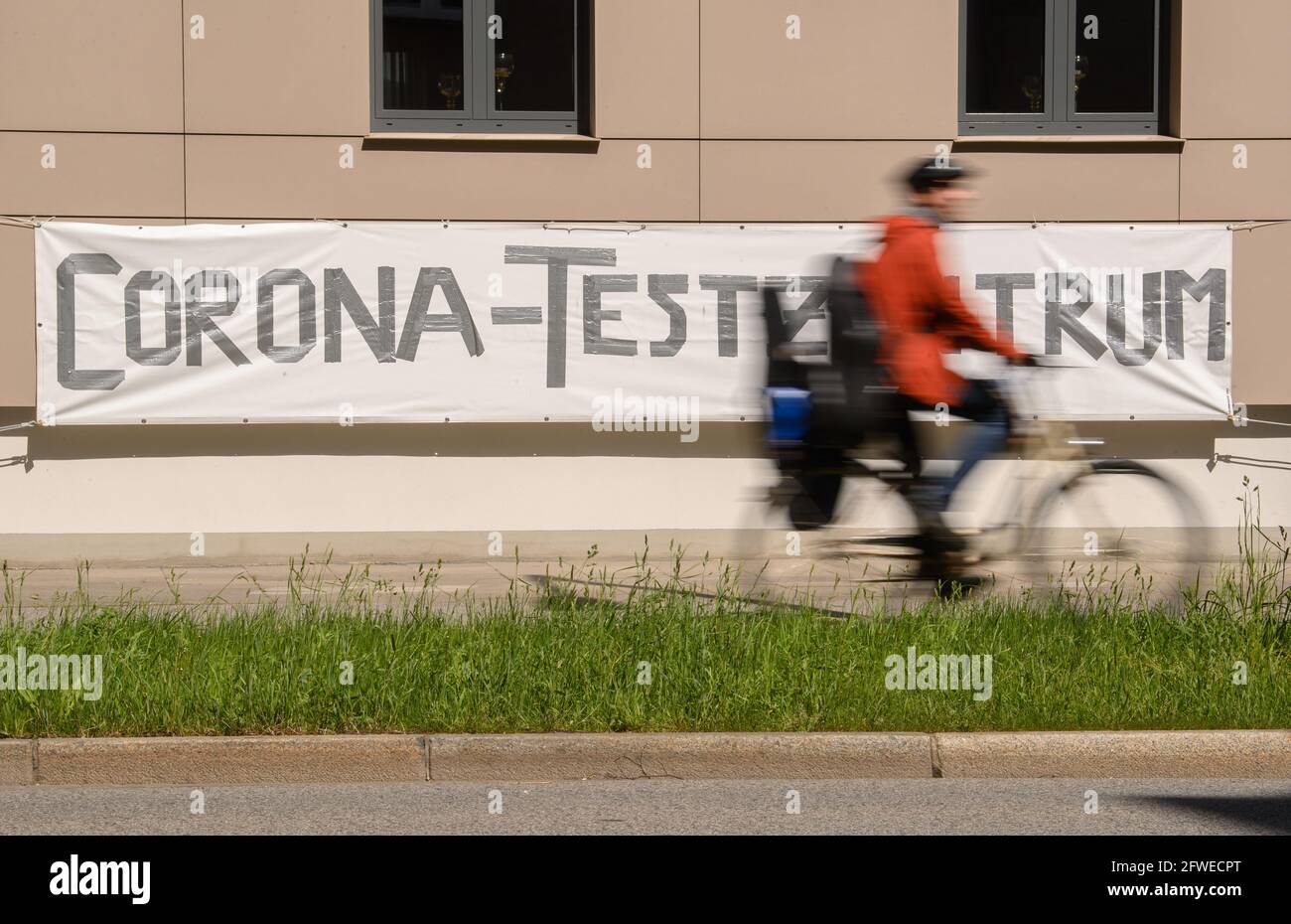 Dresden, Germany. 22nd May, 2021. A cyclist rides past a banner reading 'Corona Test Centre' in the Johannstadt district. Credit: Robert Michael/dpa-Zentralbild/dpa/Alamy Live News Stock Photo