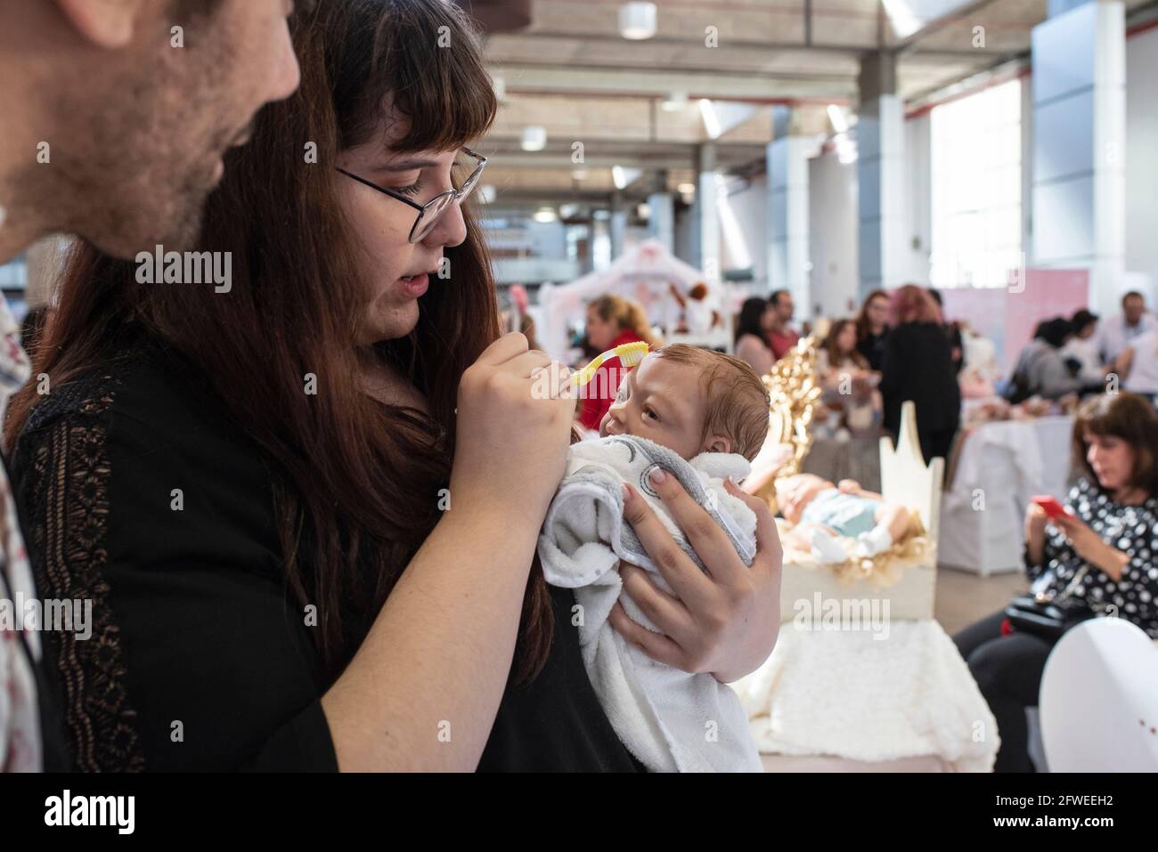 SPAIN, VALENCIA, 2019-04-28. An exhibitor covers her reborn hair with a toothbrush. Mohair goat hair implants accentuate the realism but make the baby Stock Photo