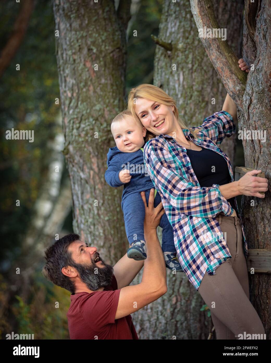 The family walks in the park in the summer, has fun, plays. Dad holds the baby in his arms Stock Photo