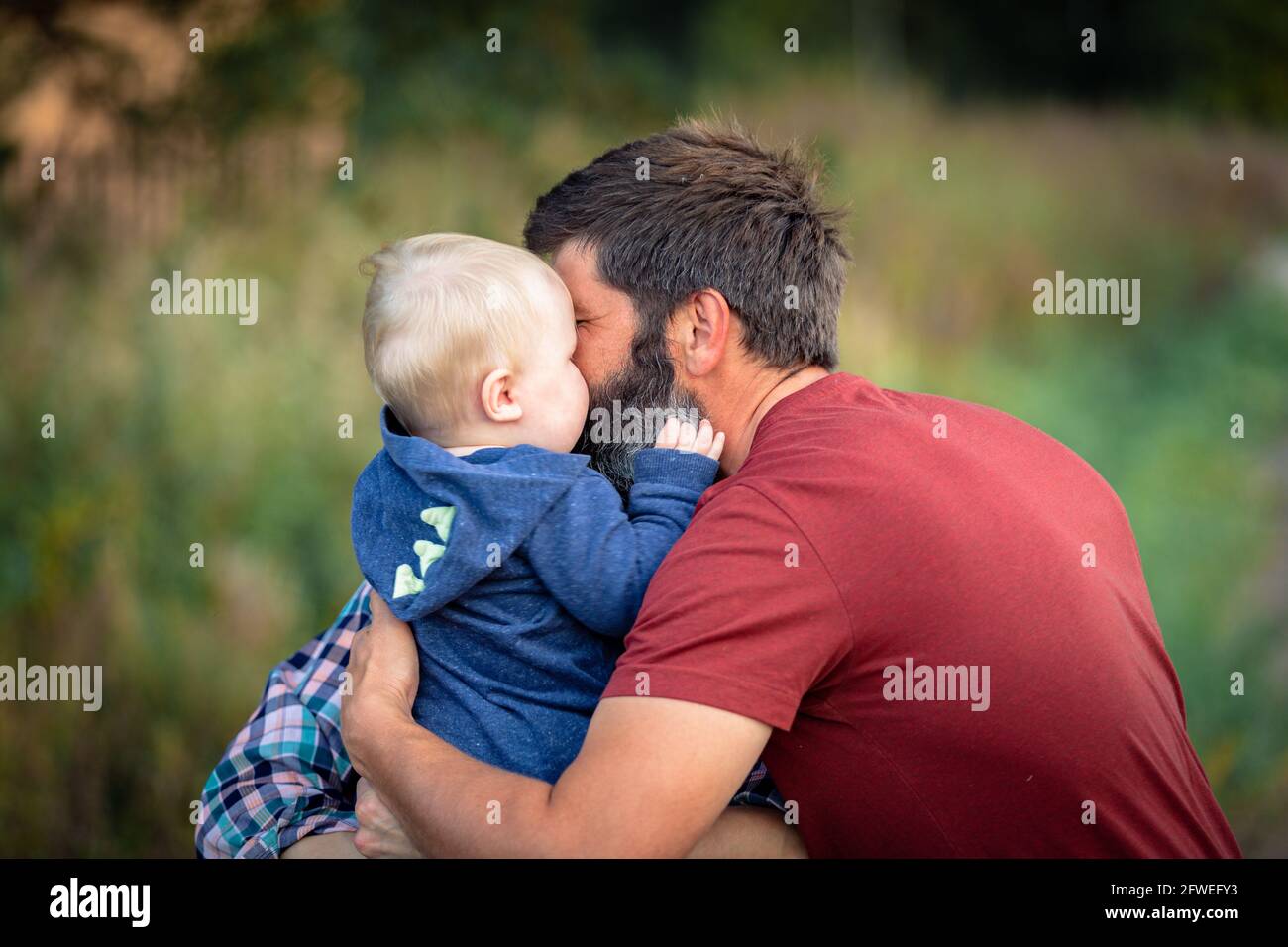 Dad plays and hugs a child walking in the park in summer. Happiness, love. Father's day Stock Photo