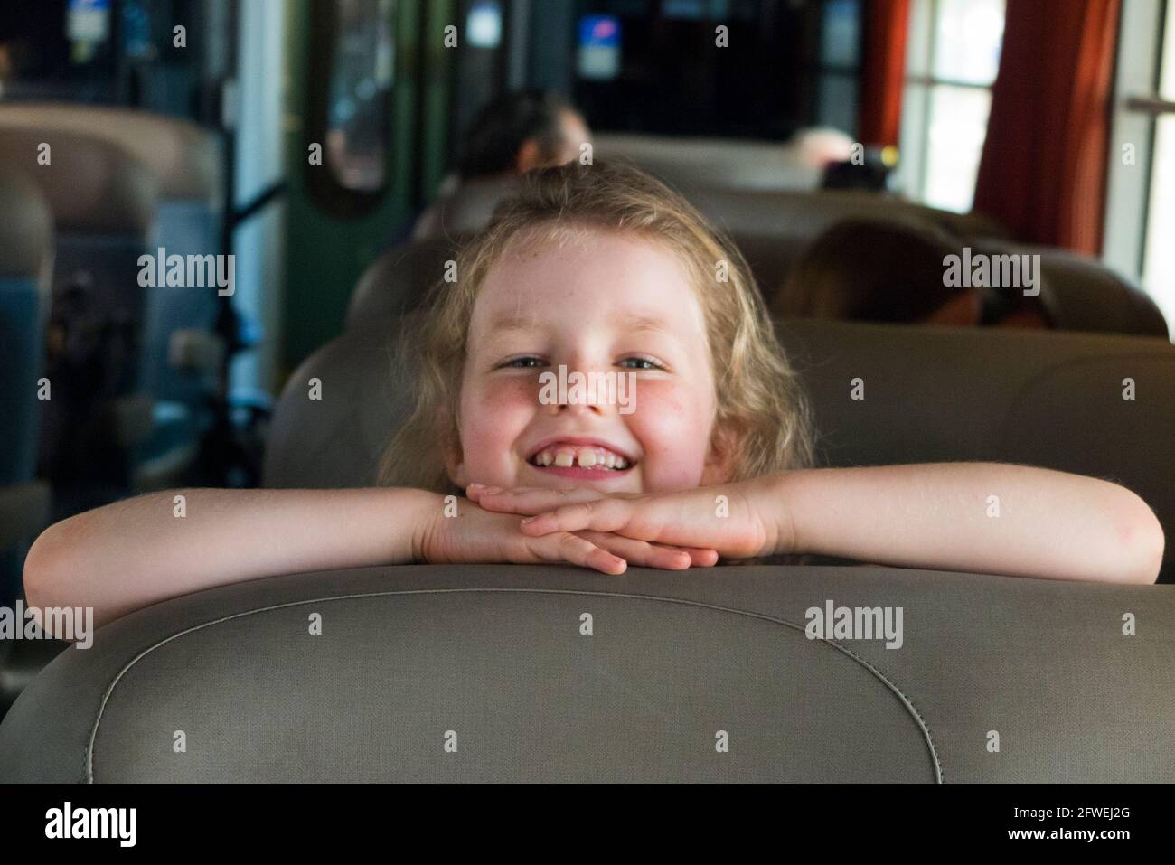 Smiling happy child / kid / girl passenger sitting on a seat on a