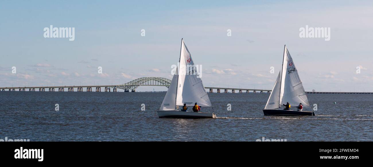 Babylon, New York, USA – 7 December 2019: Small two person sailboats in a winter regatta with the Great South Bay Bridge in the background in the wate Stock Photo