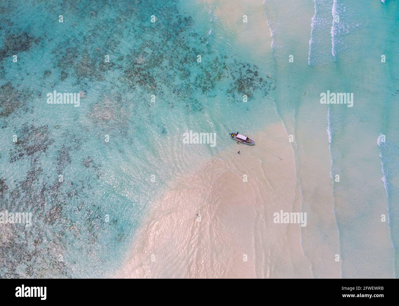 Aerial shot of the Mnemba Island white sand sandbanks washed with turquoise Indian ocean waves near the Zanzibar island, Tanzania. The couple came her Stock Photo