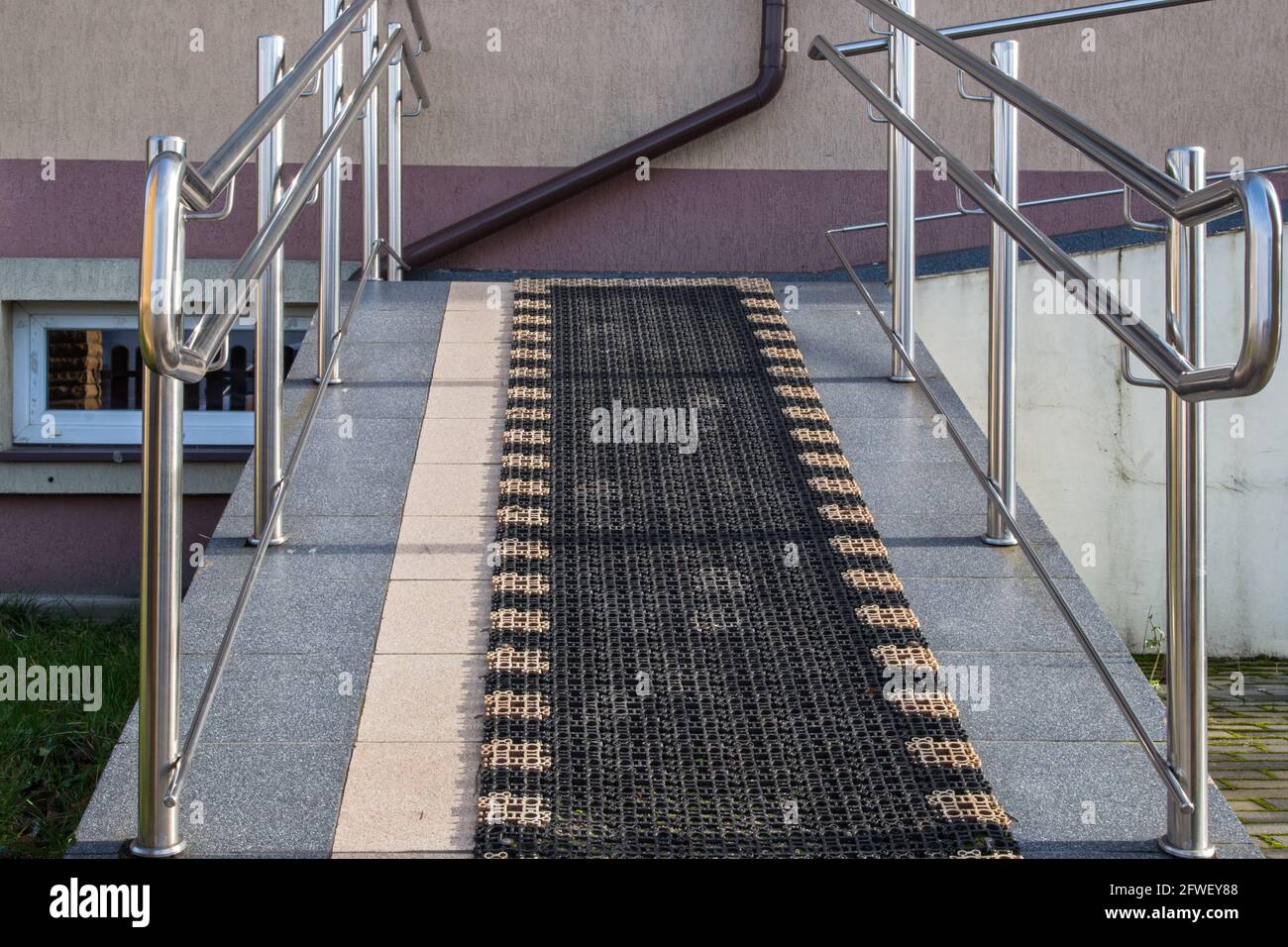 Sloping walkway surrounded by shiny handrails with antislip coating designed for wheelchair lift facility or infants in pram. Concept: social protecti Stock Photo
