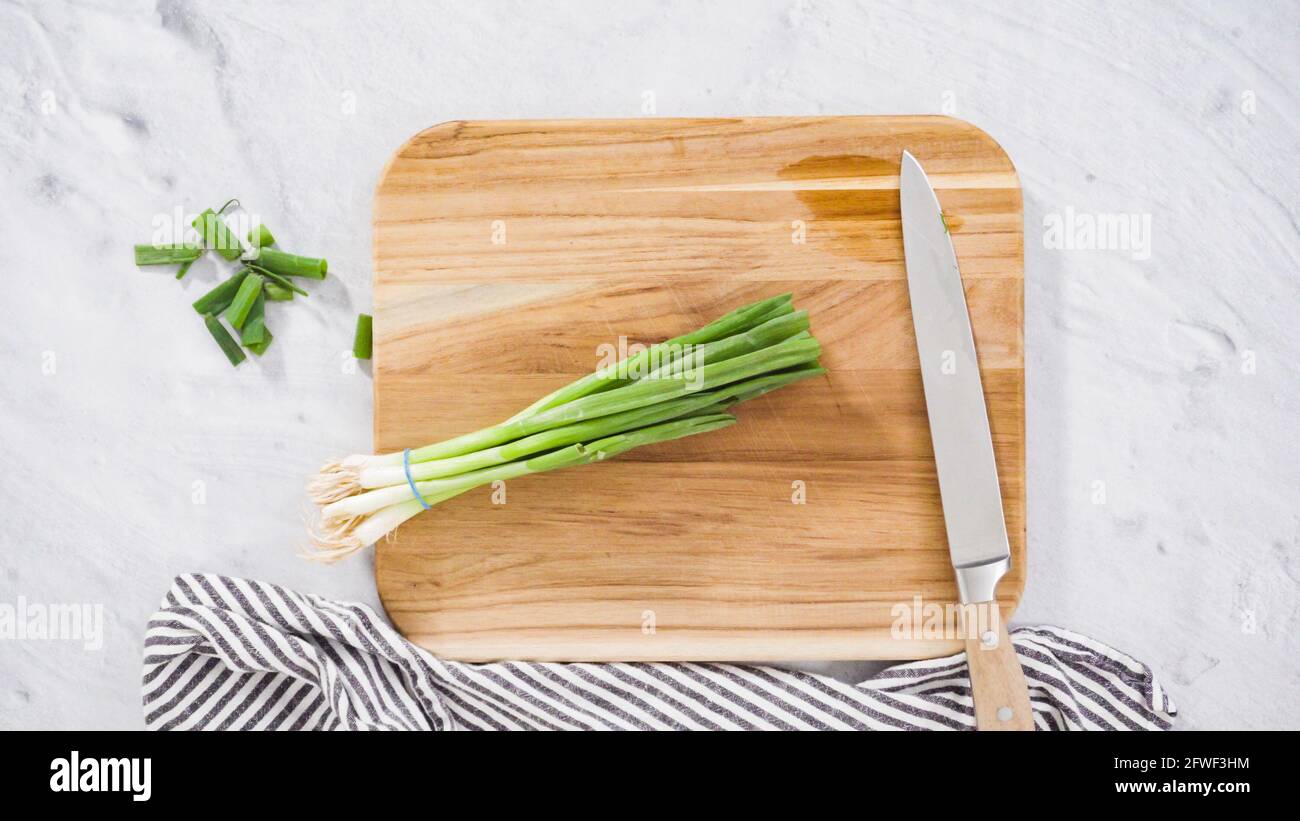 Flat lay. Step by step. Chopping organic green onions on a wood cutting ...