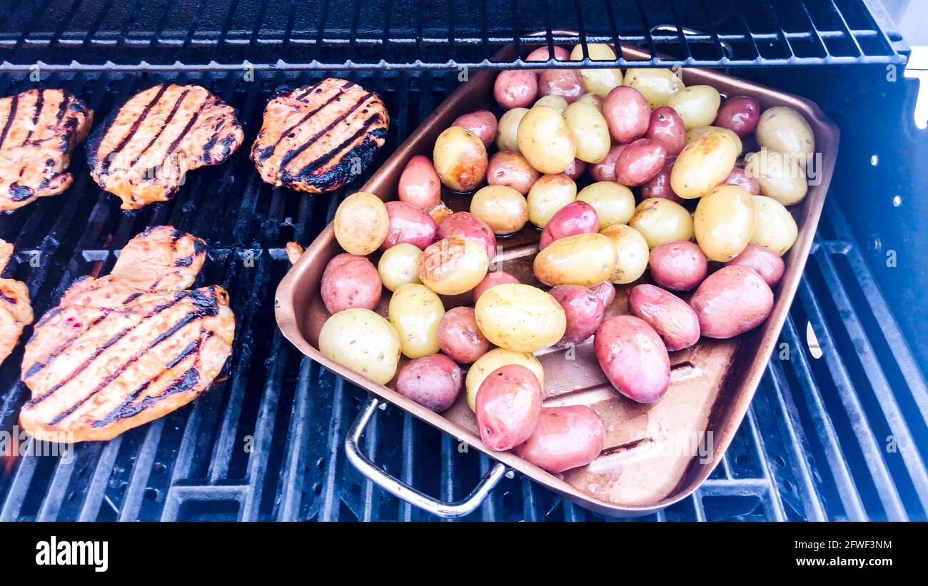 Grilling marinated chicken and small potatoes on an outdoor gas grill Stock Photo Alamy
