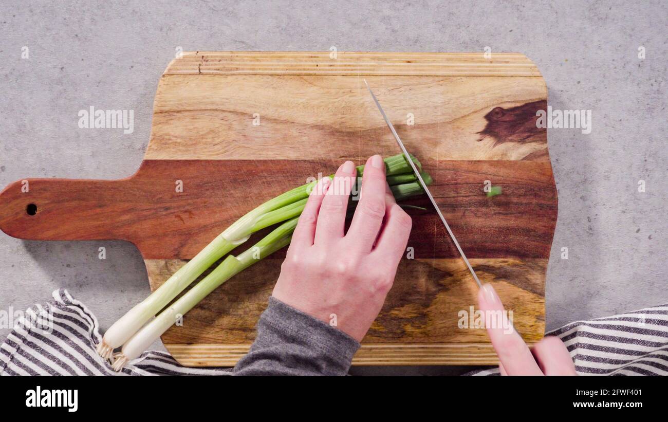 Cutting organic green onions on a wood cutting board Stock Photo - Alamy