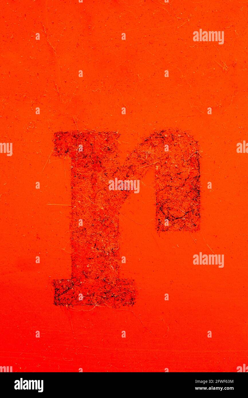 Remains of a foil letter R on an orange-red panel Stock Photo