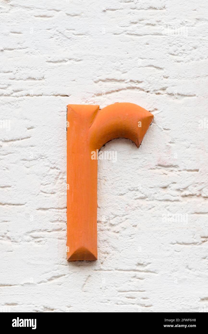 Orange letter r on a white house wall Stock Photo