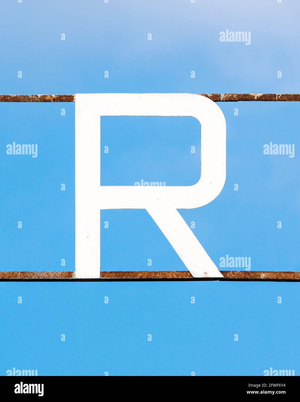 Over Bar Letter R White letter R attached to rusty metal bars against a blue sky Stock ...