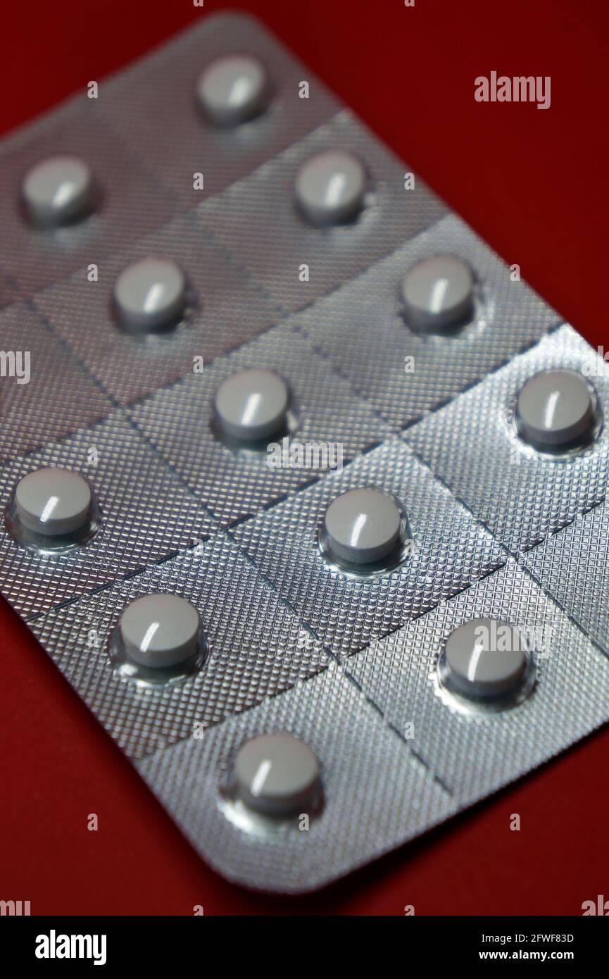 Blister pack of white pills on red background Stock Photo