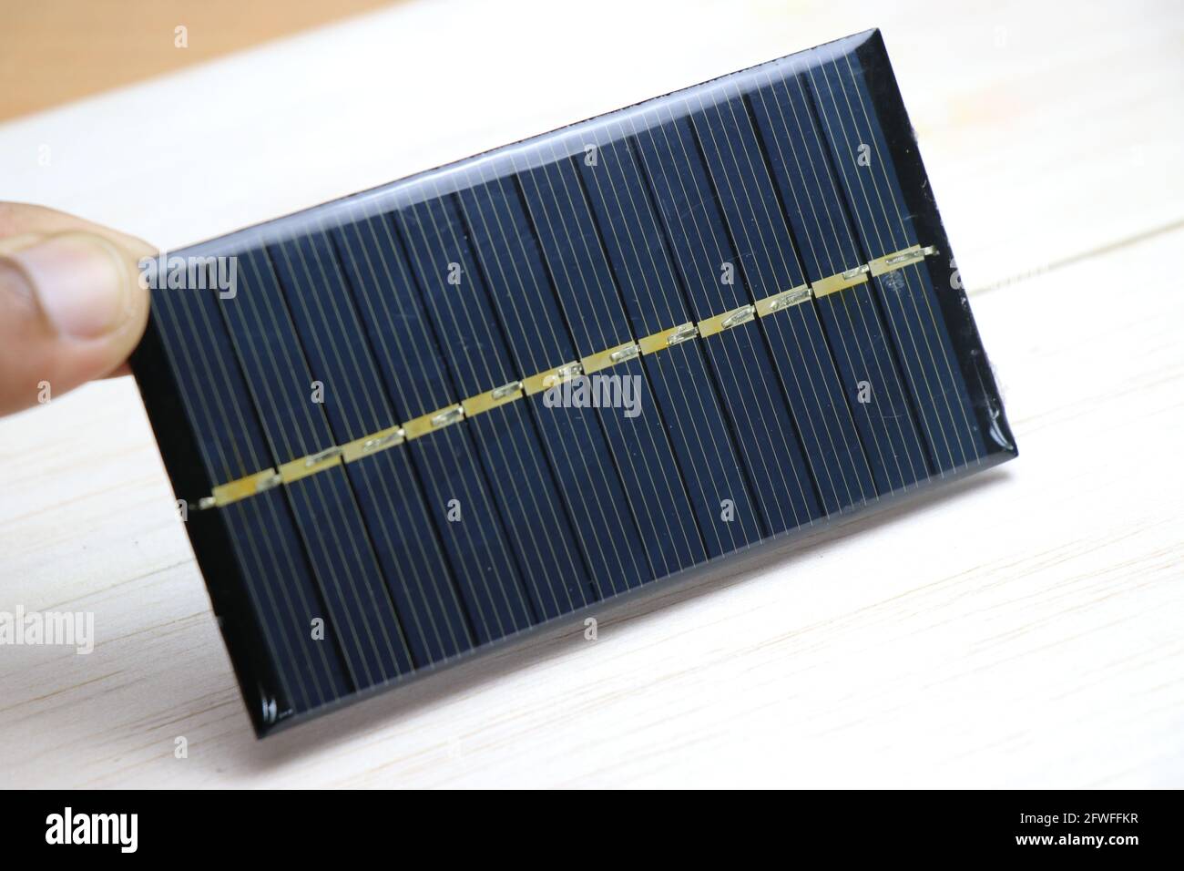Mini solar panel also called as mini solar cell which is very small in size held in hand which produces electricity when exposed to sunlight Stock Photo