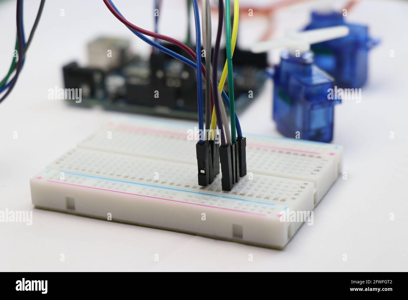 Breadboard with jumper wires connected along with arduino uno and micro servo on background. Arduino project concept Stock Photo