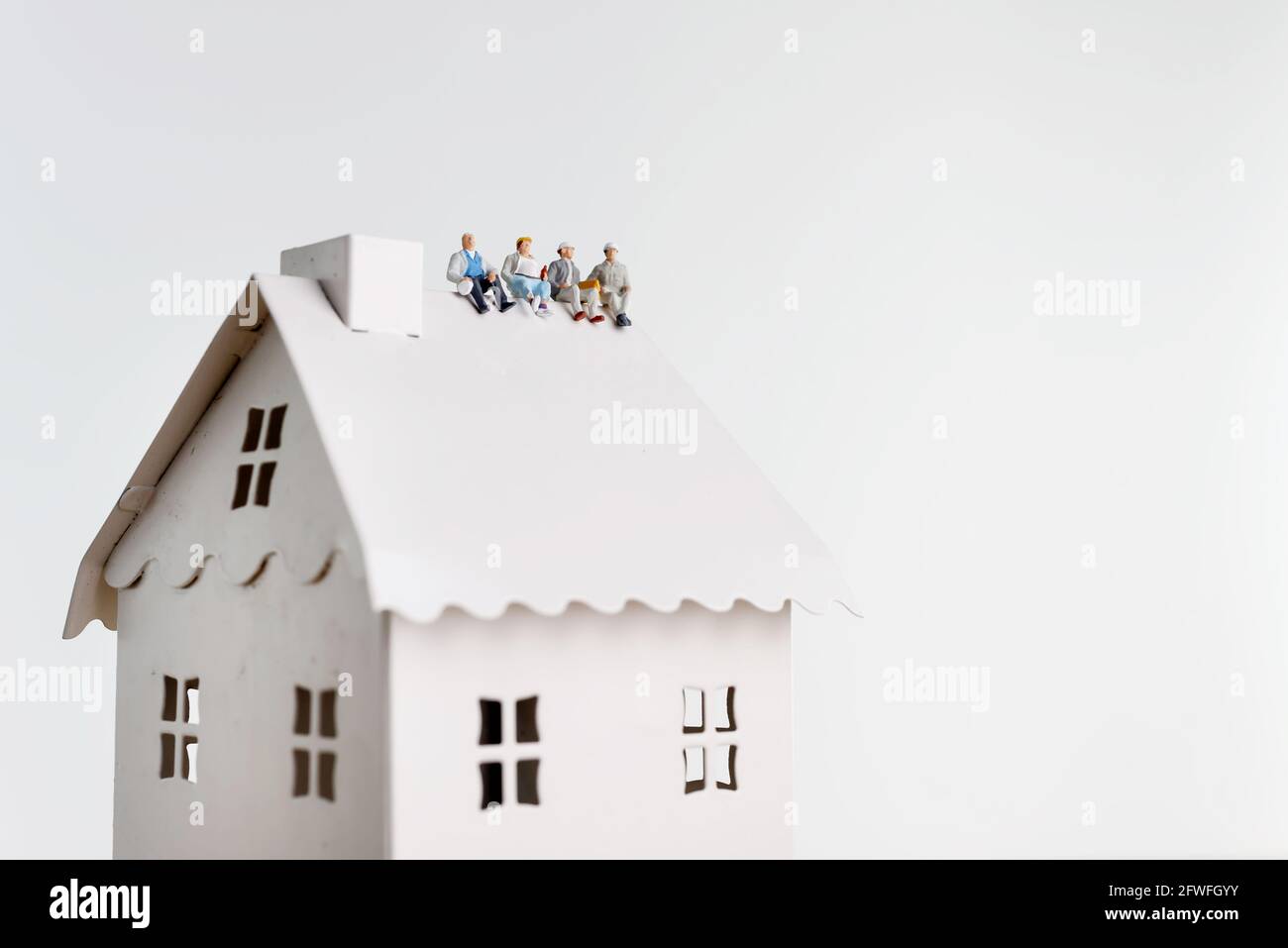 Figurines of workers having lunch on a house' roof Stock Photo