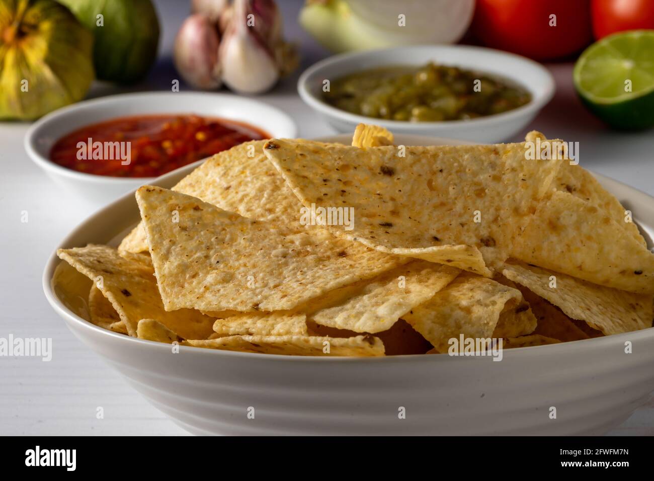 Corn tortilla chips and salsa with raw ingredients. Stock Photo