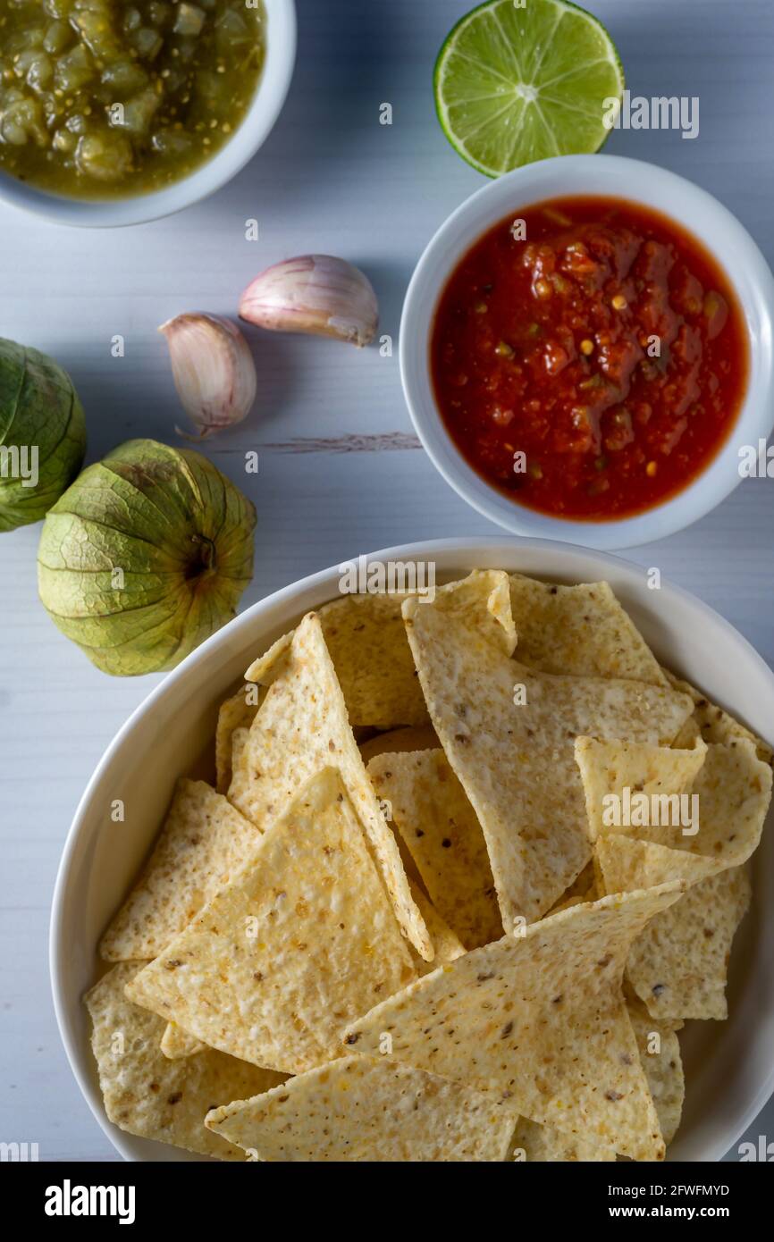 Corn tortilla chips and salsa with raw ingredients. Stock Photo