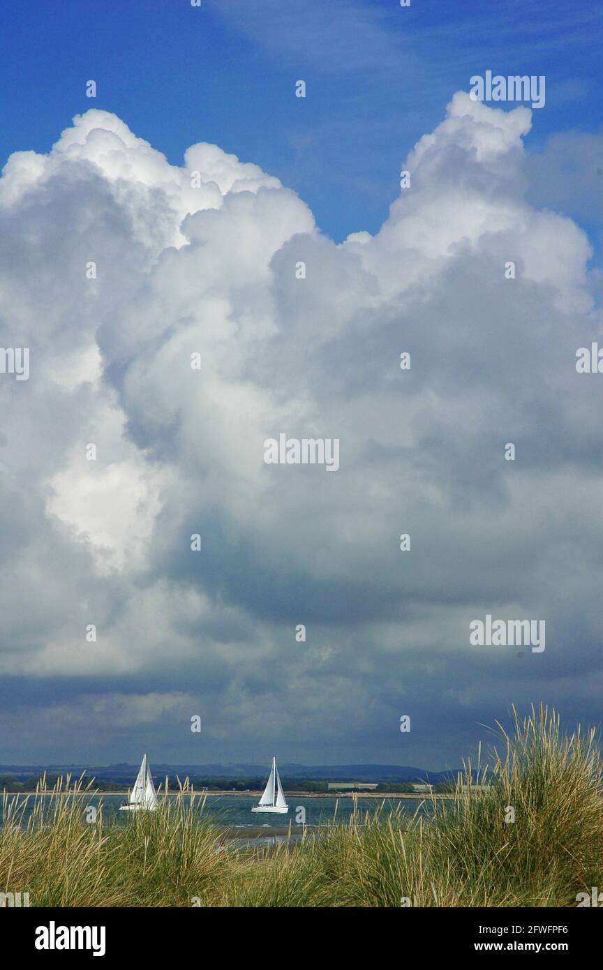 Yachts off East Head, West Wittering, West Sussex, England. September. Stormy Sky, Marram Grass, (Ammophila arenaria), Autumn, South Downs behind. Stock Photo