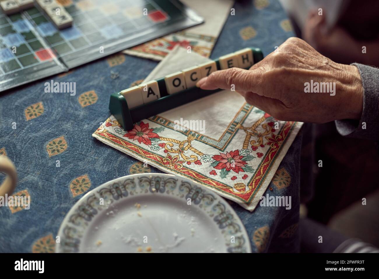 Hands of the older generation woman with arthritis, playing letters game Stock Photo