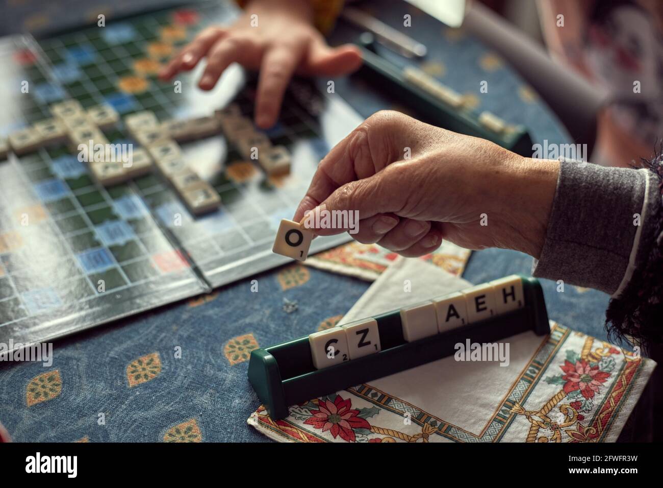 Mature hands with arthritis, playing letters game Stock Photo