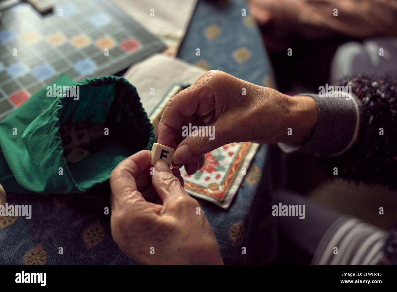 Mature hands with arthritis, playing letters game Stock Photo