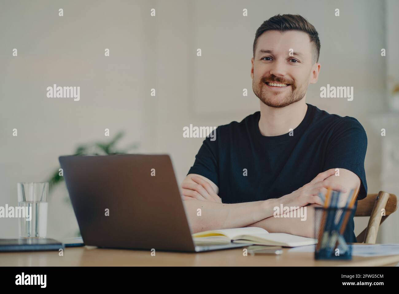 Portrait of happy businessman in casual wear sitting at his workplace in office or home Stock Photo
