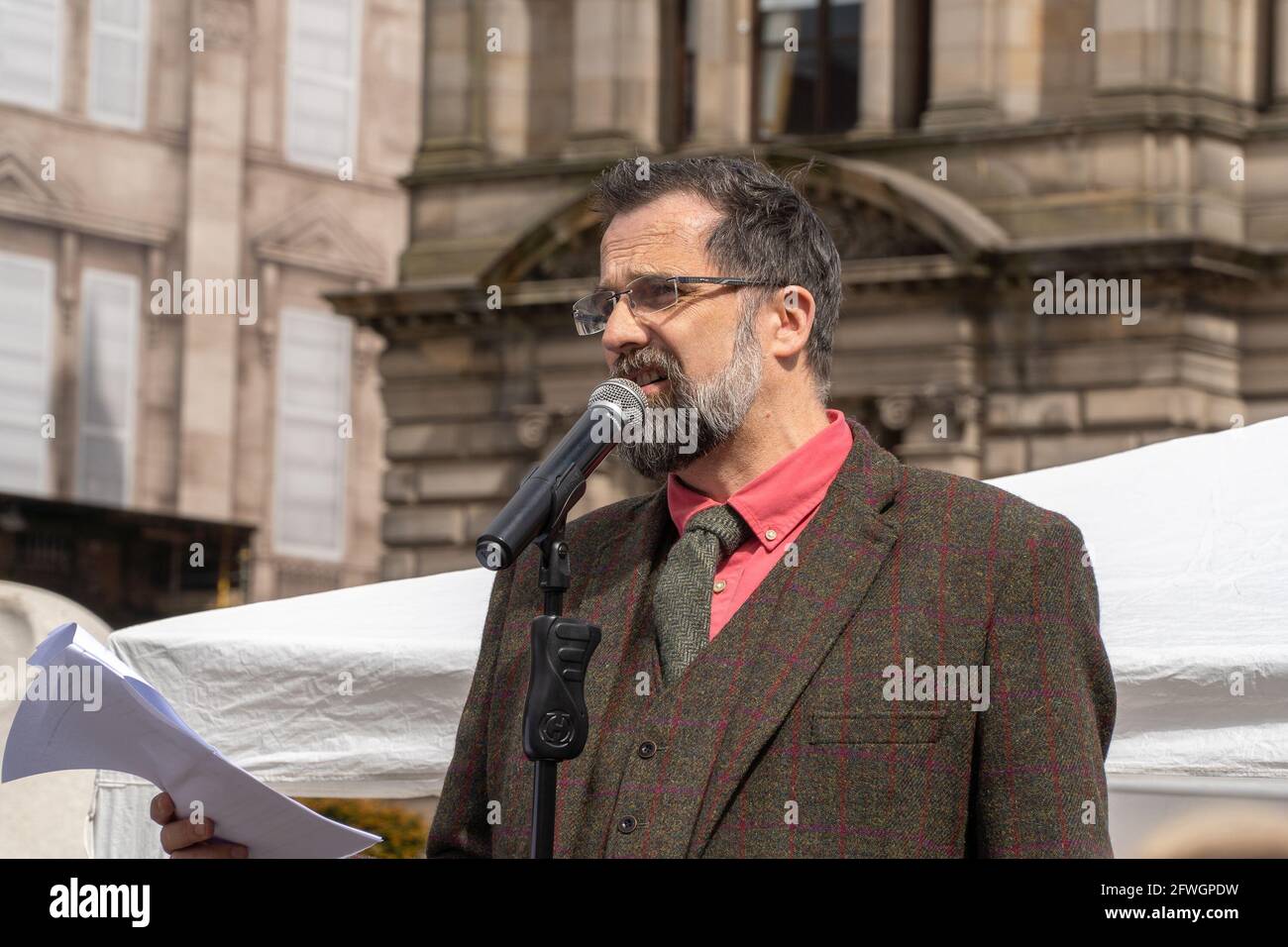 George Square, Glasgow, Scotland, UK, 22nd of May 2021: key speaker David Scott, (Northern Exposure Correspondent for The UK column) giving his speech to the large crowd gathered for an anti lockdown protest in front of the council building in George Square, Glasgow city centre, organised by (unite for truth), the event had numerous speakers addressing the crowd. They are protesting the ongoing lockdown restrictions which are seen throughout Scotland. The organisers had entertainment, which seen the crowd dancing to the music and hugging each other in excitement. The event lasted for 4 hours.  Stock Photo