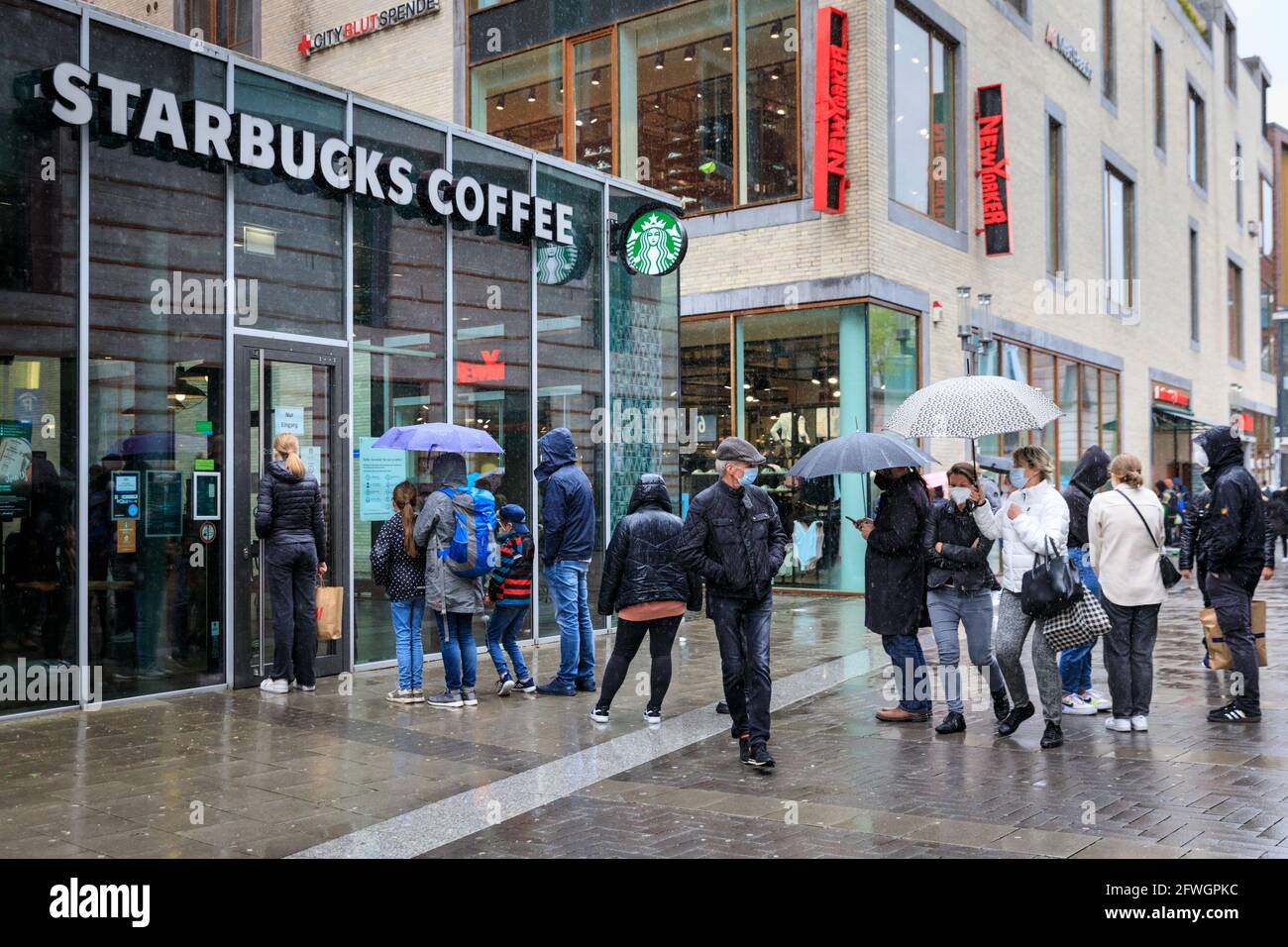 Münster, NRW, Germany. 22nd May, 2021. Queues to sit inside a Starbucks coffee shop. Crowds gather in the historic city centre of Münster, despite heavy rain, as it becomes the first city in North Rhine-Westphalia to be allowed to open up indoor drinking and dining (with negative test or vaccination), and shopping without a test or appointment (but numbers are restricted). Münster currently has one of the lowest covid incidence rates in NRW at 17/100k and has become a 'model region' to trial slow re-opening of hospitality venues. Credit: Imageplotter/Alamy Live News Stock Photo