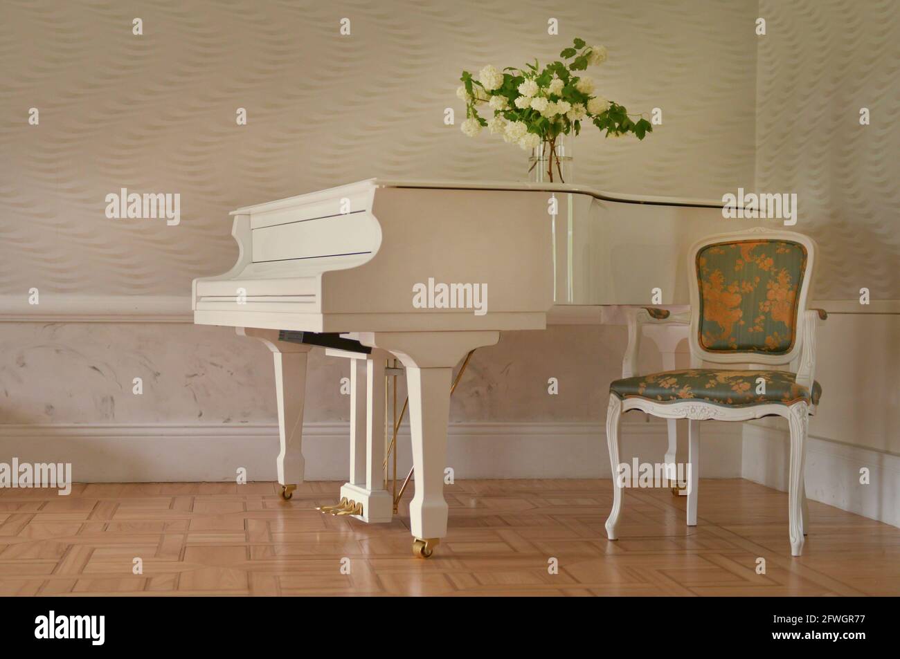 white grand piano standing in elegant white interior of palace hall.white piano at the empty reto room Stock Photo