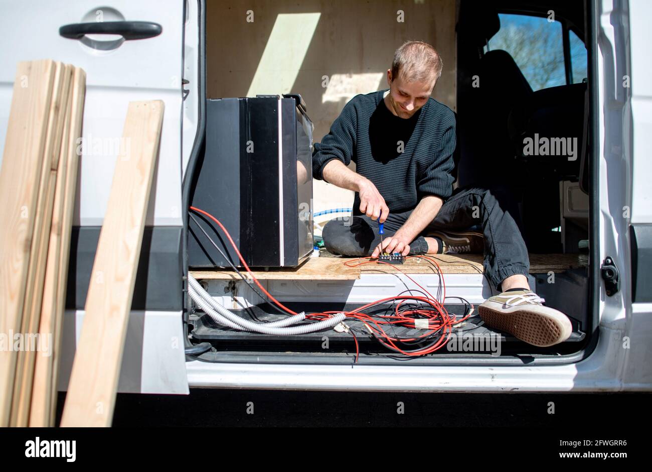 03 April 2021, Lower Saxony, Großenmeer: Hannes Wehrmann installs the electrical components in his Mercedes-Benz Sprinter, which he is converting into a campervan with his girlfriend Greta Thomas. Photo: Hauke-Christian Dittrich/dpa Stock Photo