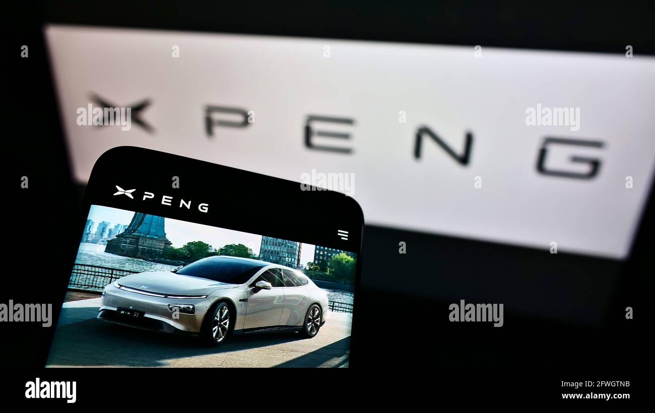 Mobile phone with webpage of Chinese electric car manufacturer Xiaopeng Motors on screen in front of logo. Focus on top-left of cellphone display. Stock Photo