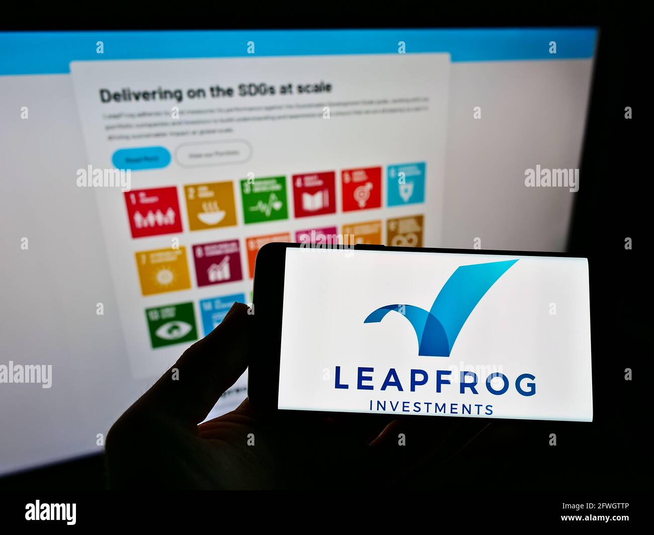 Person holding cellphone with logo of private equity company LeapFrog Investments on screen in front of business website. Focus on phone display. Stock Photo