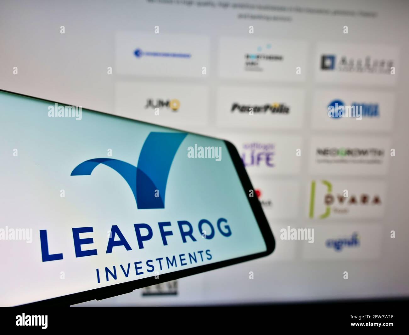 Mobile phone with logo of private equity business LeapFrog Investments on screen in front of company website. Focus on center-left of phone display. Stock Photo